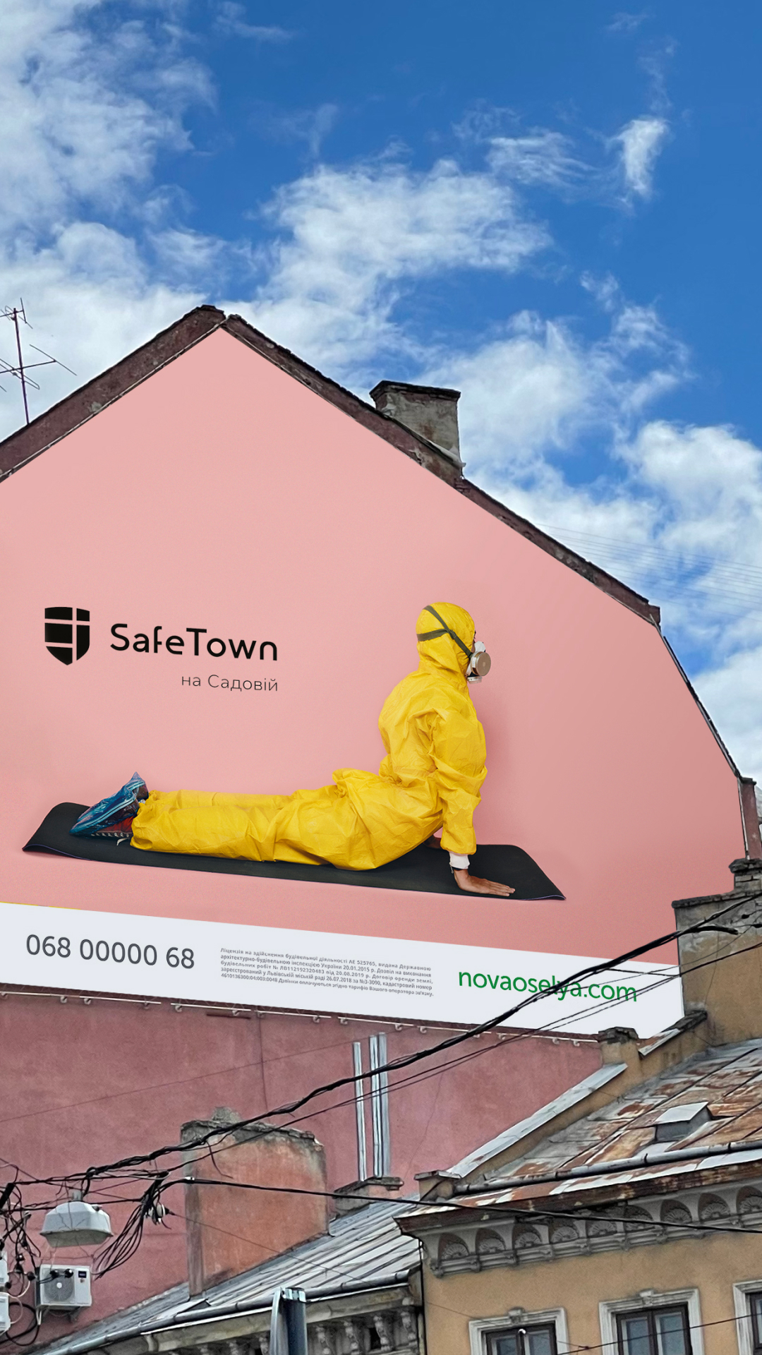 Білборд SafeTown на рожевому фасаді: людина в жовтому захисному костюмі на килимку