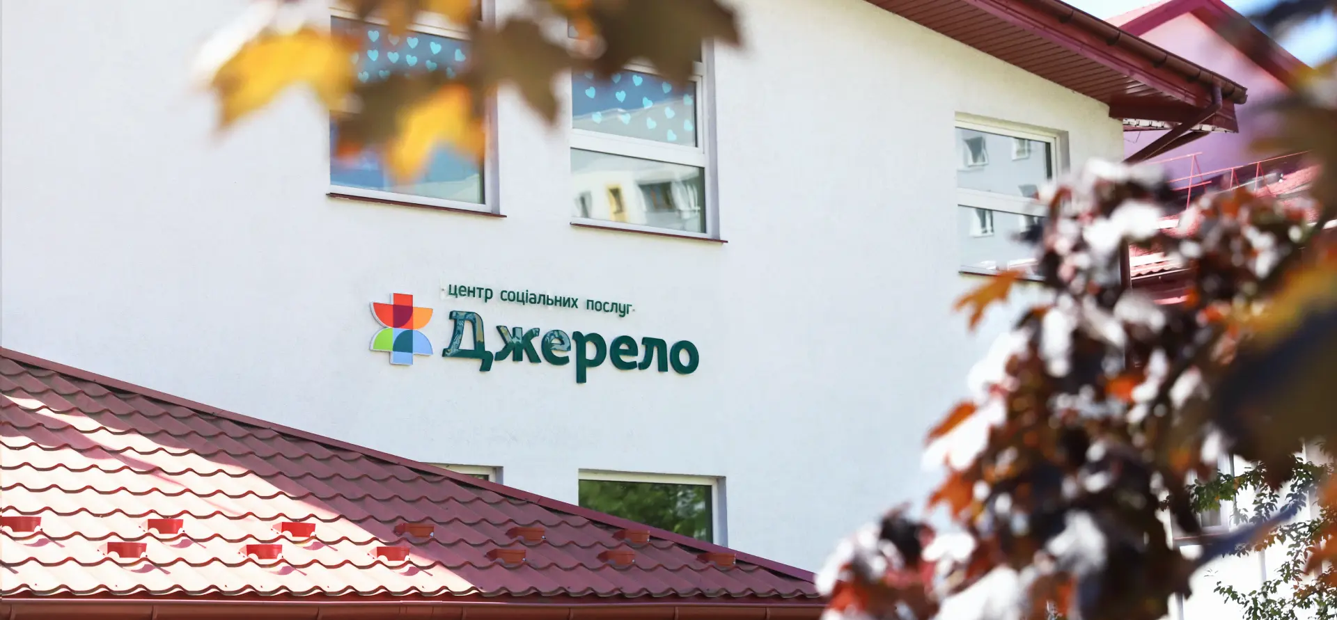 Dzherelo center building facade with its logo, framed by autumn leaves