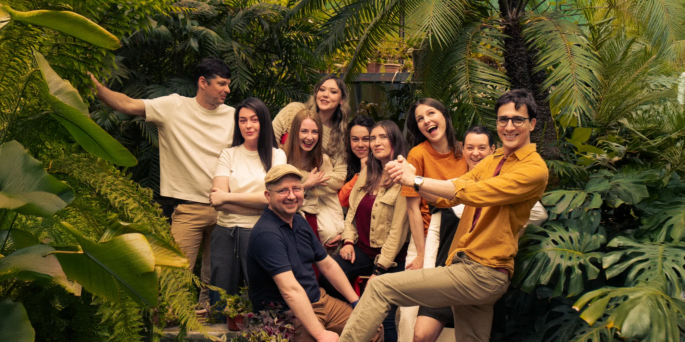 Bambuk team laughing together among tropical plants in a greenhouse