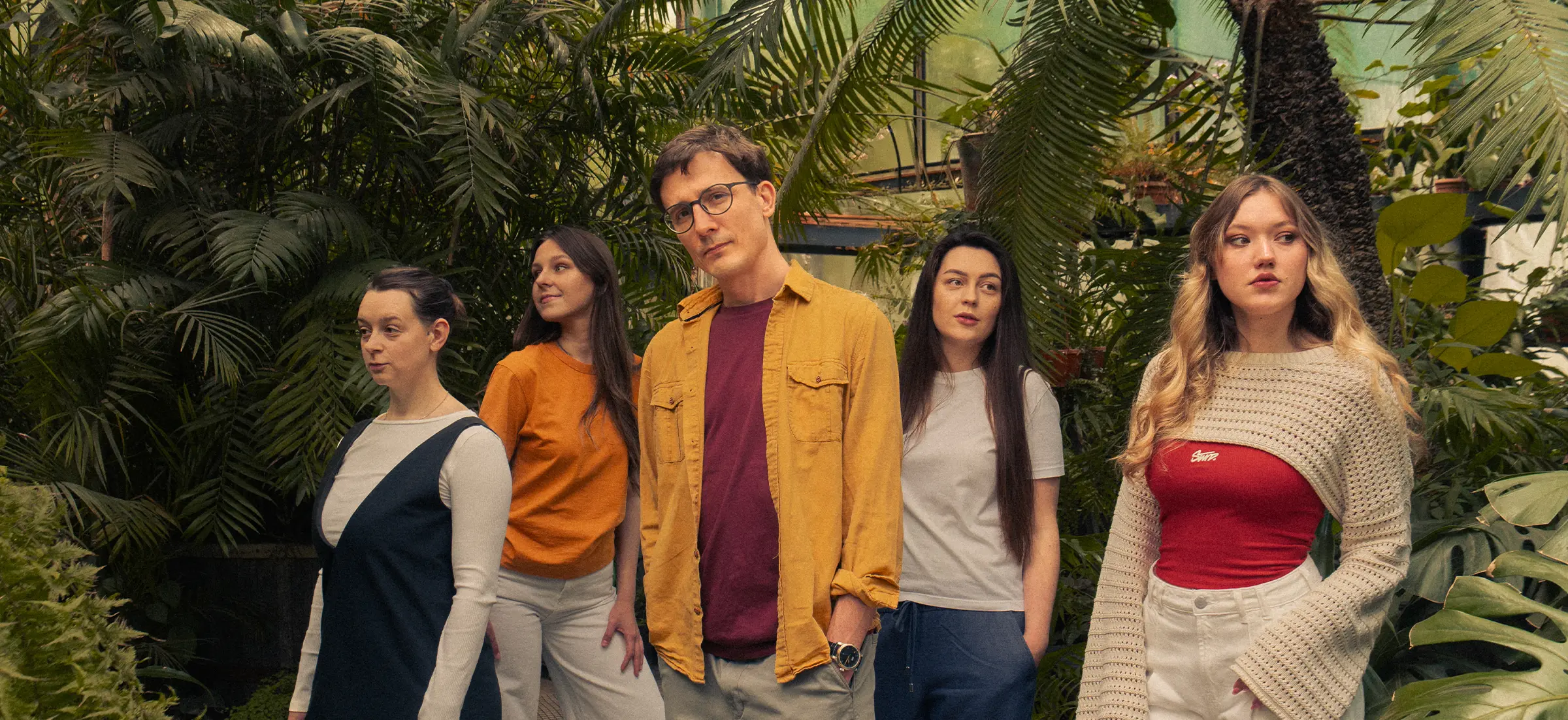 Bambuk Studio team standing among tropical plants in a greenhouse