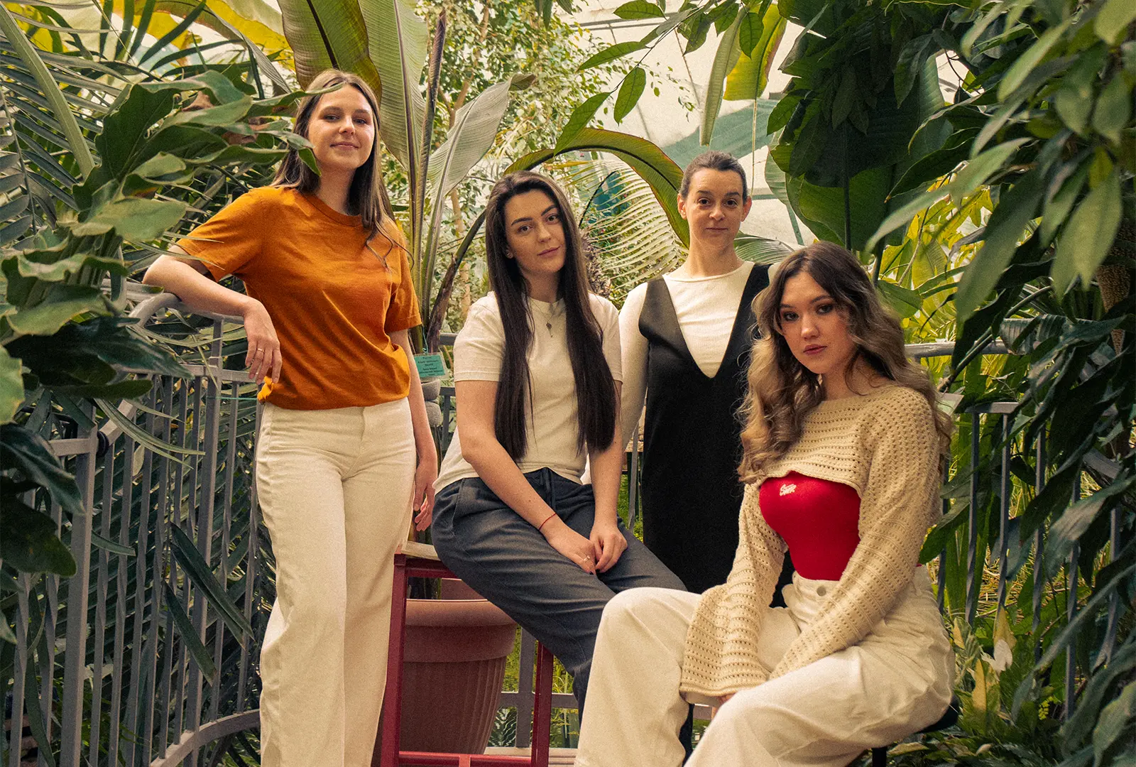 Four Bambuk Studio team members posing among tropical plants in a greenhouse