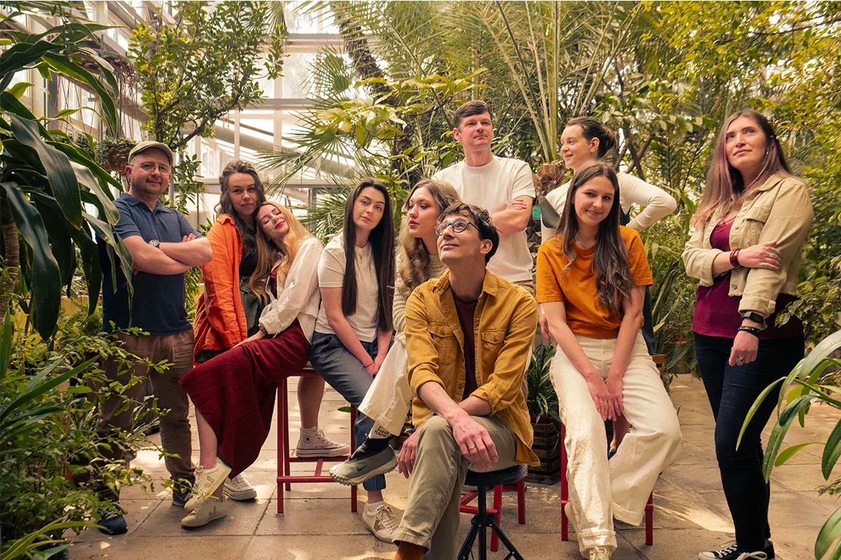 Bambuk Studio team gathered together among tropical plants in a greenhouse